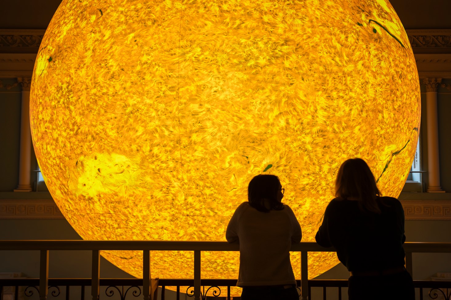 Two people admiring Helios sun sculpture